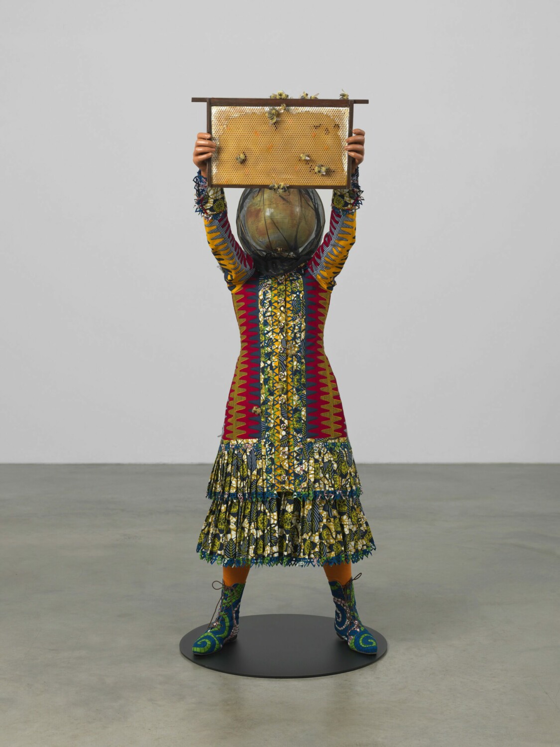 Yinka Shonibare CBE RA, 'Beekeeper Girl', 2021. Fibreglass mannequin, Dutch wax printed cotton textile, steel baseplate, bespoke globe, aluminium, nylon, brass, pine wood, paint and resin, 151 x 53 x 66cm (59 1/2 x 20 7/8 x 26in). Copyright Yinka Shonibare CBE RA. Courtesy the artist and Stephen Friedman Gallery, London. Photo by Stephen White & Co.